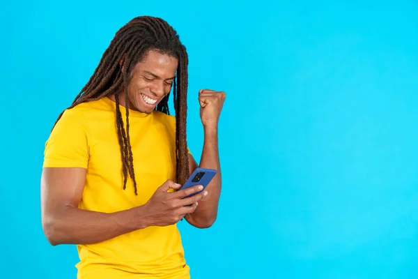 Stüdyoda Mavi Arka Planda Cep Telefonunu Kullanırken Rastalı Saçlı Heyecanlı — Stok fotoğraf