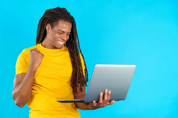 Stüdyoda Mavi Arka Planda Dizüstü Bilgisayara Bakarken Rastalı Bir Adam — Stok fotoğraf