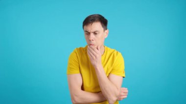 Stüdyoda mavi arka planı olan düşünceli bir adamın videosu omuzlarını silker.