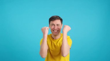 Stüdyoda mavi arka planda mutlu beyaz bir adamın yanlışlıkla bir şeyi kutladığı bir video var.