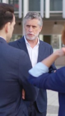 Yetişkin bir iş adamının çalışanlarına dışarıda emirler yağdırdığı yavaş çekim videosu.