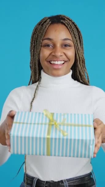 一个非洲女人在赠送礼物时对着相机微笑的蓝色背景视频 — 图库视频影像
