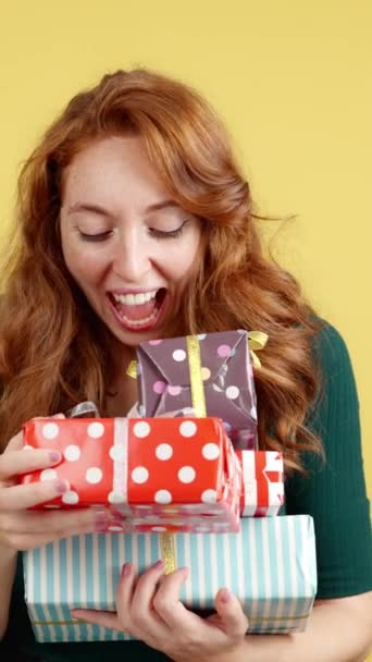 Redheaded Woman Embracing Many Gifts While Smiling Camera Studio Yellow — Stock Video