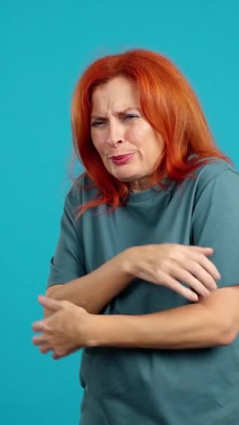 成熟的红头发女人看着镜头 在蓝色背景的演播室里摆出冷酷的姿势 — 图库视频影像