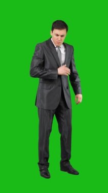 Full length of honest young male in elegant suit and tie putting hand over heart while standing against chroma key and listening to anthem