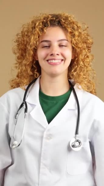 Студійне Відео Молодого Лікаря Кучерявим Волоссям Посміхається Камеру Схрещеними Руками — стокове відео