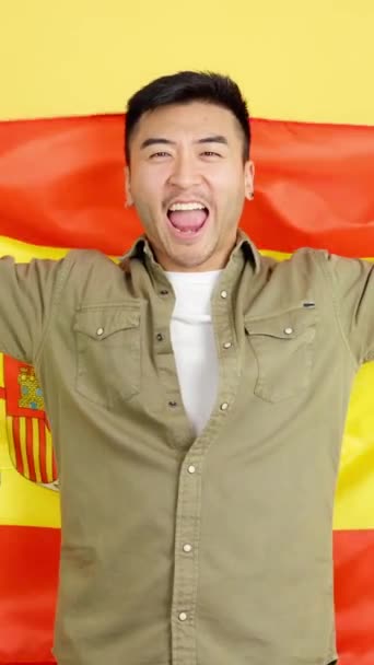Chinese Man Smiling Raising Spanish National Flag Studio Yellow Background — Video Stock
