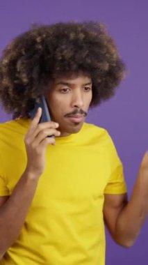 Angry african man with curly hair talking to the mobile in studio