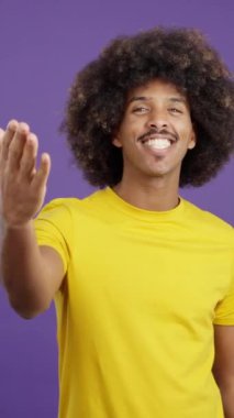 Stylish african man blowing a kiss in studio on purple background