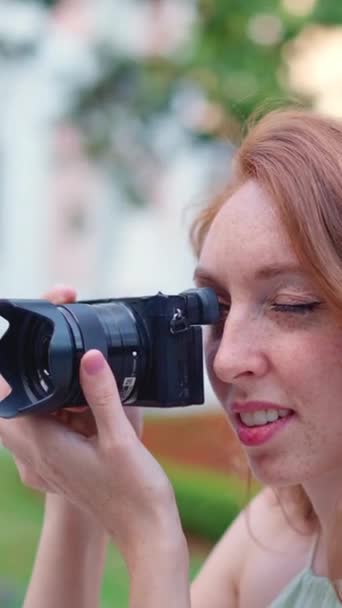 公園の隣の通りで写真を撮る赤髪の白人女性の姿を間近に見る — ストック動画
