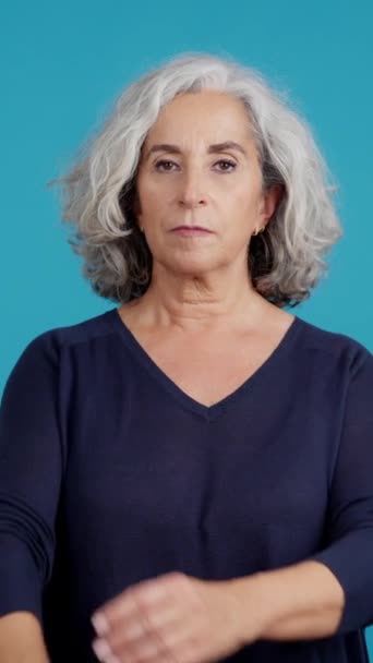 Студийное Видео Голубым Фоном Серьезной Взрослой Женщины Смотрящей Камеру Скрещенными — стоковое видео