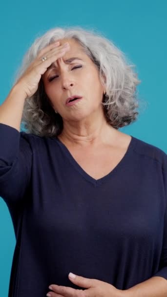 Studio Video Blue Background Mature Woman Headache Touching Her Forehead — Stockvideo