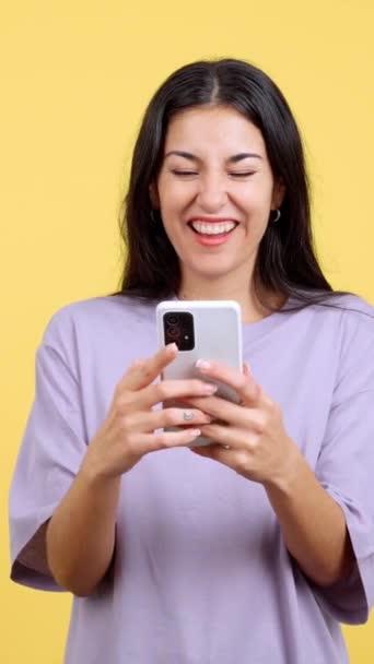 Захоплена Жінка Святкує Під Час Використання Мобільного Телефону Студії Жовтим — стокове відео