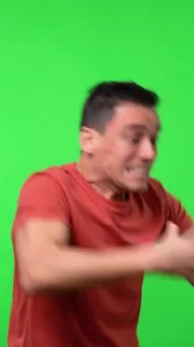 Çok kızgın bir adam, kontrolsüz hareket ediyor, kırmızı gömlek giyiyor. Orta boy. Krom yeşil arkaplan.