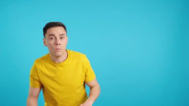 Stüdyoda mavi arka planlı, şaşırmış bir adamın anlamadığı bir şeye hayretle baktığı bir video.