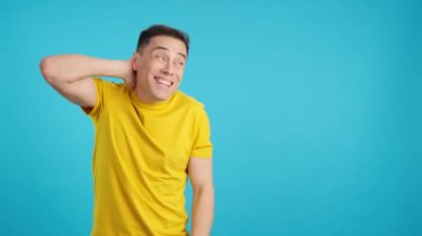 Stüdyoda mavi arka planda utangaç bir adamın el kol hareketi ve bakışlarıyla