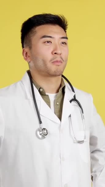 Médico Chinês Amigável Uniforme Estetoscópio Estúdio Com Fundo Amarelo — Vídeo de Stock