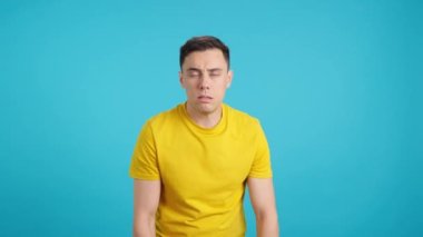 Stüdyoda soğuk algınlığı olan bir adamın mavi arka planlı videosu var.