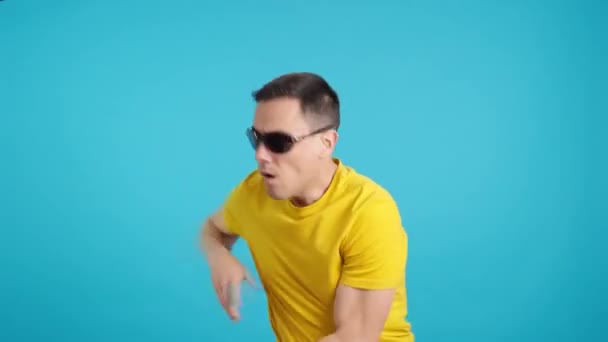 Video Studiu Modrým Pozadím Zdrogovaného Muže Slunečními Brýlemi Tančící Nekontrolovatelně — Stock video