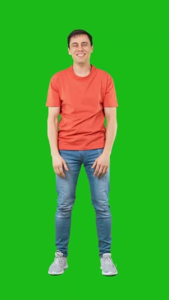 フルボディ幸せな男性でジーンズとオレンジTシャツストレッチ腕と包含しようとするカメラ隔離された緑の背景 — ストック動画