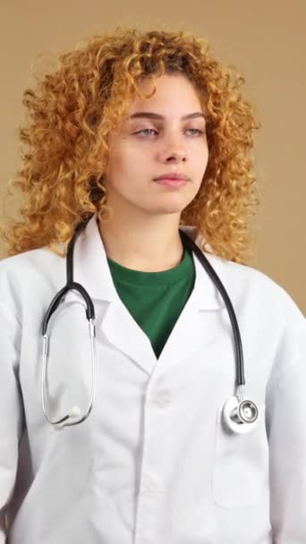 工作室录像 一位年轻而严肃的女医生 卷曲的头发 身穿实验室外套 双臂交叉 想模仿空间 — 图库视频影像