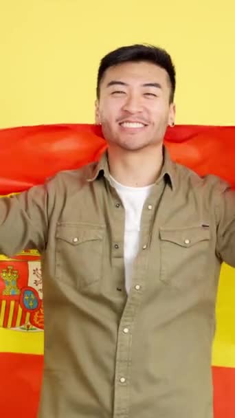 Glad Kinesisk Man Tittar Kameran Insvept Spansk Nationell Flagga Studio — Stockvideo