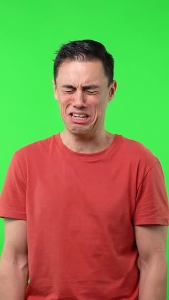 必死に泣いてる男 赤いシャツ ミディアムショットで クロマグリーンの背景 — ストック動画
