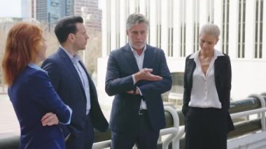 Yetişkin bir iş adamının iş arkadaşlarıyla sokakta konuşmasının yavaş çekim videosu.