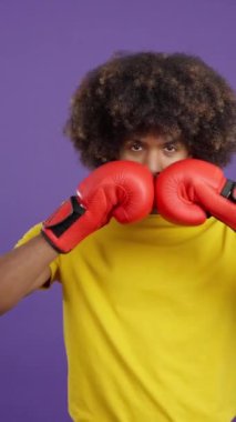 African man with boxing gloves in fight pose looking at the camera in studio