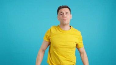 Stüdyoda elleri parayı simgeleyen bir adamın mavi arka planlı videosu var.