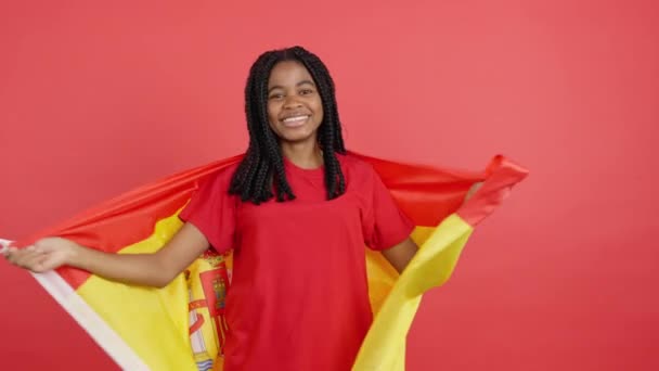 Счастливая Африканка Заворачивающая Испанский Национальный Флаг Студию Красном Фоне — стоковое видео