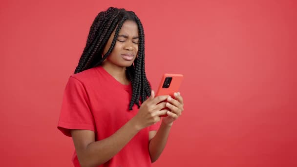 Besorgte Afrikanerin Benutzt Handy Studio Mit Rotem Hintergrund — Stockvideo