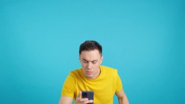 Stüdyoda cep telefonuna bakarken elini kaldıran bir adamın mavi arkaplanlı videosu. Çerçeve boş başlar, adam aşağıdan görünür ve altta kaybolur..