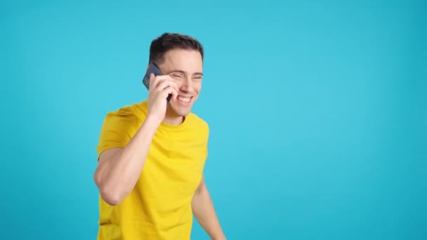 Videó Stúdióban Kék Háttérrel Amin Egy Boldog Férfi Beszél Mobiltelefonnal — Stock videók