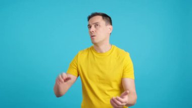 Huysuz ve hayal kırıklığına uğramış bir adamın kameraya alaycı bir şekilde alkışladığı mavi arka planlı bir video.
