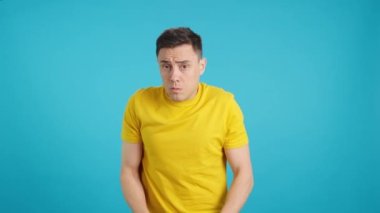Stüdyoda mavi arka planı olan güvensiz bir adamın etrafa bakındığı bir video.