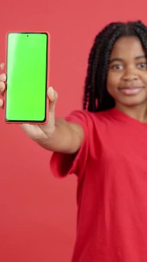 Stüdyodaki kırmızı arka planı olan Afrikalı kadının cep telefonunun boş ekranı.
