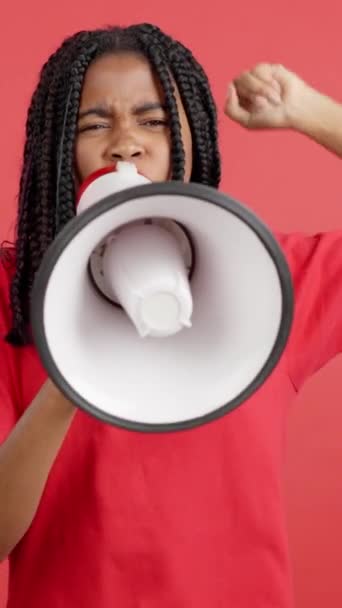在有红色背景的工作室里 非洲女人用扩音器大喊大叫 这让人很不安 — 图库视频影像