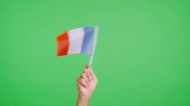 Stüdyoda bir elin krom renginde Fransa bayrağının bayrağını sağa sola salladığı yavaş çekim videosu.