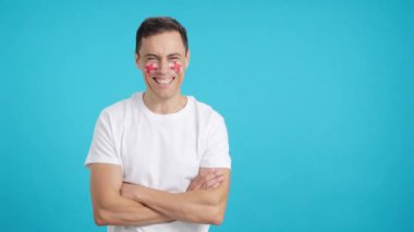 Stüdyoda, yüzünde İngiliz bayrağı olan kollarını kavuşturarak gülümseyen bir adamın kromasıyla.