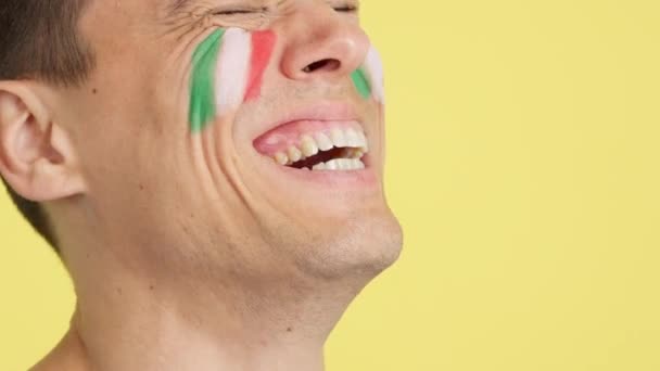 ハッピーな男のスタジオでビデオを閉じる スペインの旗が空白のコピースペースに目をそらす顔に描かれています — ストック動画