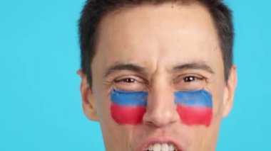 Stüdyoda Haitili bir adamın yüzünü destekleyen Haiti bayrağıyla boyamış bir adamın krom görüntüsü var.