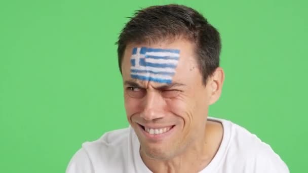 在演播室里用彩色的特写录像拍摄一个脸上涂有希腊国旗的非常紧张的男人 在一场比赛中支持希腊球队 这场比赛最终以失败告终 — 图库视频影像