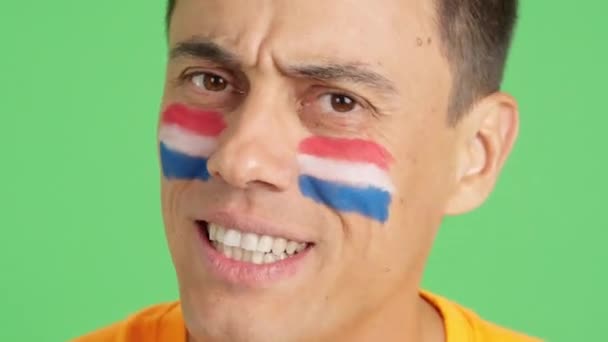 在演播室里用彩色的近距离录像拍摄一个脸上涂有杜奇旗的非常紧张的男人 在一场比赛中支持杜奇团队 这场比赛最后以失败告终 — 图库视频影像