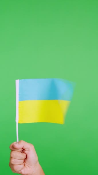 Slow motion video in studio with chroma of a hand lifting a ukrainian pennant while waving by the wind