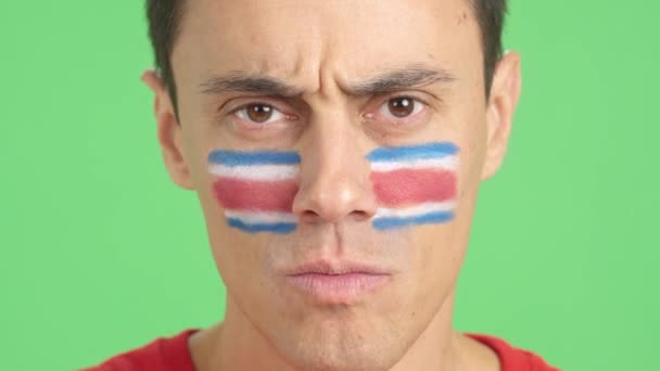 摄影棚里的录像 彩色的是一个严肃男子的特写 他的脸上挂着一面意大利面的国旗 看着镜头 — 图库视频影像