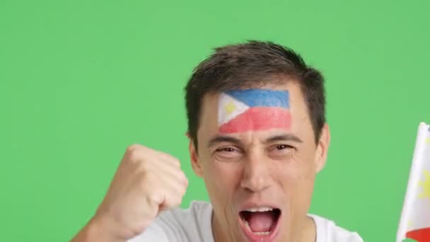 影片在演播室里的彩色特写是一个男人的特写 他的脸上挂着菲律宾国旗 支持菲律宾团队 — 图库视频影像