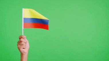 Rüzgâr, el ele tutuşan Kolombiyalı bir flamayı sallıyor. Yavaş Hareket videosu