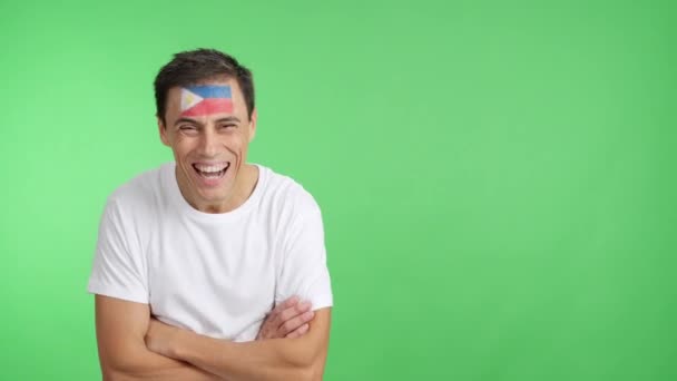 スタジオでのビデオ 腕と顔に笑顔で描かれたフィリピンの旗と立っている男のクロマ — ストック動画