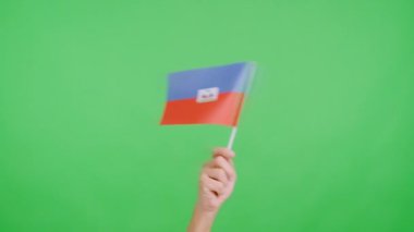 Stüdyoda, Haiti bayrağının bayrağını sağa sola sallayan bir elin kromasıyla yavaş çekim videosu.